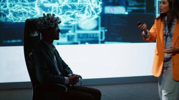Speaker does EEG headset presentation during tech convention, demonstrating successful implementation of AI in driving forward startup businesses, sharing latest neuroscience discoveries, camera A video