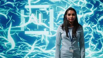 Portrait of smiling IT specialist standing with arms crossed in front of cutting edge display featuring AI and neural network graphics. Researcher in startup doing advancements in AI field, camera A video