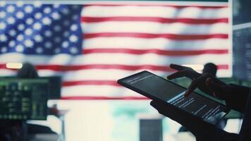 Cybersecurity expert in a governmental IT environment with the American flag. Monitoring cybersecurity, encryption and data security on a tablet to protect against cyber threats. Close up. Camera B. video