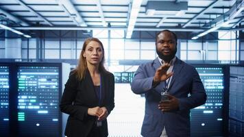 Teamworking colleagues looking at holograms in data center, working together. Server hub IT staff members doing brainstorming and interacting with augmented reality AI visualization, camera B video