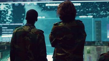 Diverse team of military personnel examining gathered information from CCTV satellite footage, transmitting crucial data to field troops. Army officers work on defense in command center. Camera A. video