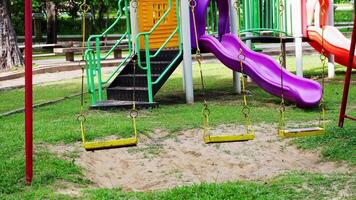 A colorful playground slide and swing on sandy park grounds for children. video