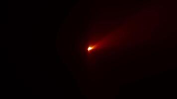 The center of the glow is a golden-red beam of light. optical lens flares shine animation on black abstract background. shine ray video