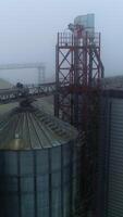 Grain containers and warehouses at the present day elevator complex. Huge silo premises in the foggy weather day. View from above. video