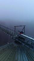 Sloping roof of an elevator tank with massive metal support over it. Drone footage along the metal pillar on the cistern. Foggy winter forest backdrop. video