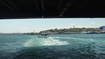 Passing Underneath Historic Bridge from Boat, Capturing Wake in Clear Blue Waters, Urban Skyline in Background, Emphasizing Contrast Between Modern Urban Life and Serene Maritime Travel video