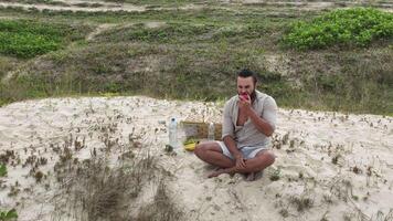 Man eating fruit and drinking water during picnic on the beach. Frontal Camera. video