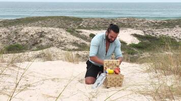 Man eating fruit and drinking water during picnic on the beach. Frontal Camera. video