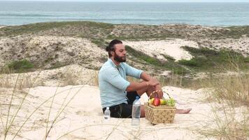 Man eating fruit and drinking water during picnic on the beach. Frontal Camera. video