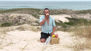 Man eating fruit and drinking water during picnic on the beach. Frontal Camera. video