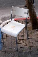 A lounge chair stands on the sidewalk on a street in a big city. photo