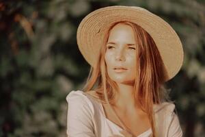 Woman with straw hat stands in front of vineyard. She is wearing a light dress and posing for a photo. Travel concept to different countries photo