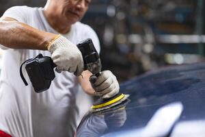 Car polishing, Worker in Auto workshop using color polisher machine. Polish coating wax in car care. photo