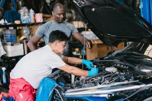 Mechanic team men working together to service fix engine problem in car auto workshop photo