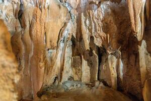 A cave with a lot of rocks and a lot of dirt. The cave is dark and the walls are brown. photo