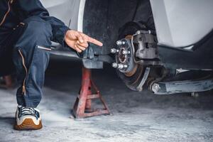 Closeup Mechanic man hand pointing at car front disc breaking system service replace broken part. Center Bore Part. photo