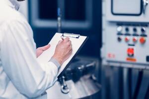 Scientist Medical Factory Staff Working in Science Lab. Medicine factory Technician Employee Check Care Products Quality in Sterilize Room Taking Note in Check list. photo