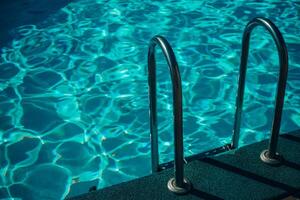 A metal ladder is in the water. The water is clear and calm. The ladder is in the middle of the pool. photo