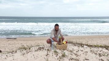 Man eating fruit and drinking water during picnic on the beach. Frontal Camera. video