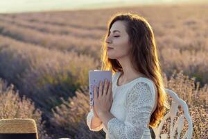 A woman is sitting in a field of lavender flowers, holding a book in her lap. She is in a peaceful and serene mood, possibly enjoying a quiet moment of reading or reflection photo