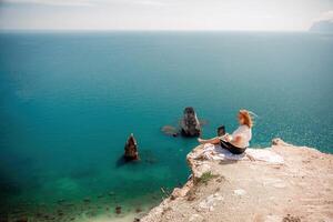 Freelance woman working on a laptop by the sea, typing away on the keyboard while enjoying the beautiful view, highlighting the idea of remote work. photo