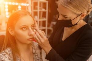 Make-up artist working with brush on model eyes Close up of applying make up on young girl,semi profile, professional make up in beauty studio photo