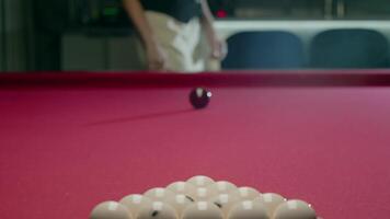 Woman is getting ready for a Russian pyramid game. She opens a case and takes out a professional cue. In front of her, on the billiards table, there are billiards balls arranged in a triangle. Mid shot. Slow motion video