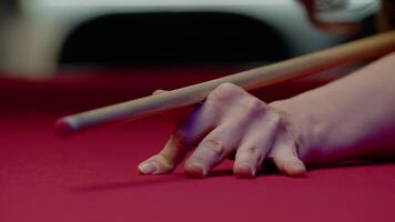 Woman's hand is gracefully positioned in the bridge stance on the billiards table, preparing to make a precise shot. Close up. Slow motion video