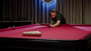 Man hits a group of white balls arranged in a triangular pattern with a well-aimed shot, causing them to scatter across the billiards table. video