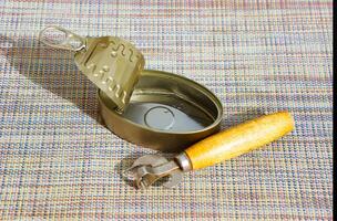 An old can opener opens an empty tin can photo