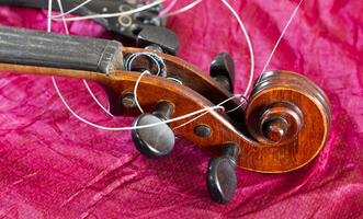 Broken violin and tangled strings, on a red background. photo