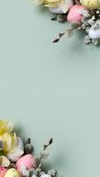 Daffodils, easter eggs and willow on green background with copy space. Easter greeting card template vertical format photo