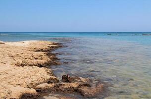 Rocky beach of the Mediterranean Sea, seaside resort of Cyprus island, Protaras. The stones are visible from the clear sea water on a sunny summer day. Natural daylight. Natural wallpaper photo
