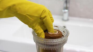 Plumber working in yellow protective gloves holds a dirty water filter in his hand. Dirty rusty filter for water purification. Multi-stage water filter cartridge replacement video