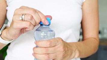 Bottle with stationary plastic cap in woman hand. The new design means the cap remains attached to the bottle after opening, making the entire package easier to collect and recycle. 4k footage video