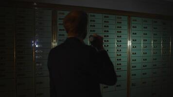 A man searches in secure deposit boxes with a flashlight to find hidden clues and assets video