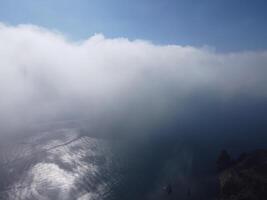 Aerial view. The drone flies over foggy and fluffy clouds. Blue sky sun and sea fog. Abstract aerial nature summer ocean sunset sea and sky background. Vacation, travel and holiday concept photo