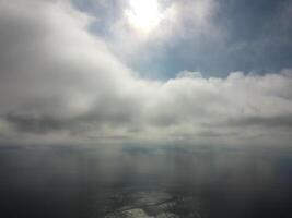 Aerial view. The drone flies over foggy and fluffy clouds. Blue sky sun and sea fog. Abstract aerial nature summer ocean sunset sea and sky background. Vacation, travel and holiday concept photo