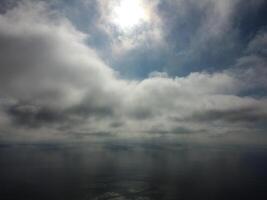 Aerial view. The drone flies over foggy and fluffy clouds. Blue sky sun and sea fog. Abstract aerial nature summer ocean sunset sea and sky background. Vacation, travel and holiday concept photo
