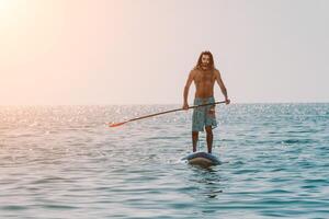 Man Sup Sea. Strong athletic man learns to paddle sup standing on board in open sea ocean on sunny day. Summer holiday vacation and travel concept. Aerial view. Slow motion photo