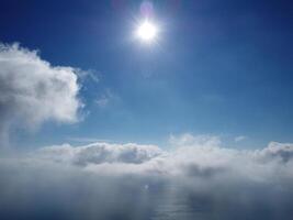 Aerial view. The drone flies over foggy and fluffy clouds. Blue sky sun and sea fog. Abstract aerial nature summer ocean sunset sea and sky background. Vacation, travel and holiday concept photo