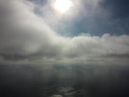 Aerial view. The drone flies over foggy and fluffy clouds. Blue sky sun and sea fog. Abstract aerial nature summer ocean sunset sea and sky background. Vacation, travel and holiday concept photo