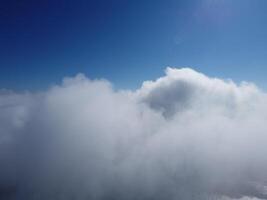 Aerial view. The drone flies over foggy and fluffy clouds. Blue sky sun and sea fog. Abstract aerial nature summer ocean sunset sea and sky background. Vacation, travel and holiday concept photo