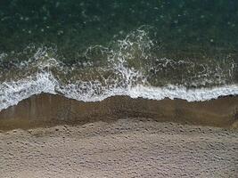 Aerial view from above on calm azure sea and volcanic rocky shores. Small waves on water surface in motion blur. Nature summer ocean sea beach background. Nobody. Holiday, vacation and travel concept photo