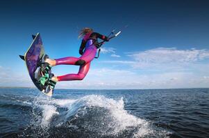 professional kiter performs a difficult trick on a beautiful background with splashes of water from the sea and a cloudy sky photo