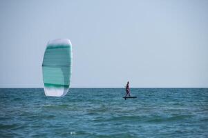 Man using kiteboarding wing and hydrofoil board doing extreme sports on sea and ocean water. Hydrofoil photo