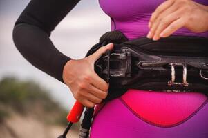 Summer sports. Kitesurfing on a lake or sea, a woman is preparing to launch a kite. Girl's hands and trapeze close-up photo