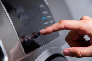 Close-up of a hand selecting a program with a finger while pressing on a washing machine photo