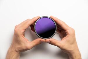 polarizing filter for camera in male hands on a white background, close-up photo