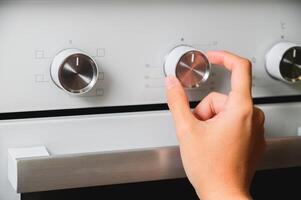 Using an oven, close-up of oven temperature control. A woman's hand sets the temperature at the oven photo